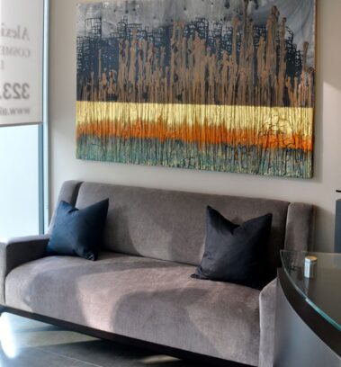 Gray couch with picture hanging on wall above it.