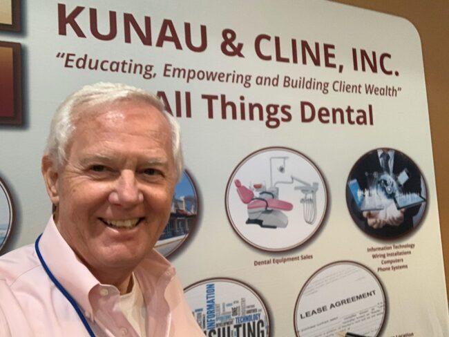 Cliff Houser posing in front a poster that says "All Things Dental".