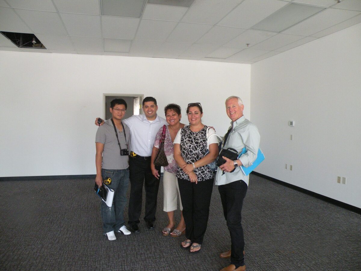 Cliff Houser posing for a pictures with clients in empty room.