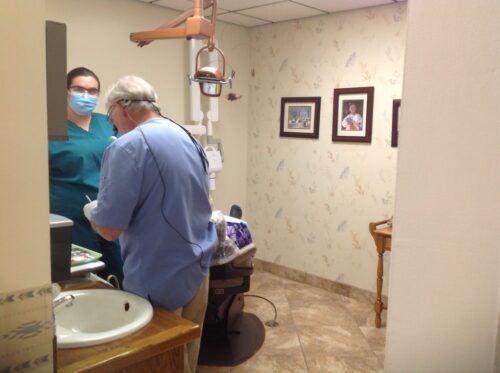 A male Dentist and a female assist get ready to work on a patient.