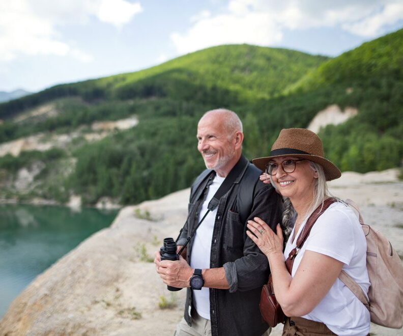 Smiling and happy senior couple hiking in the mountains.